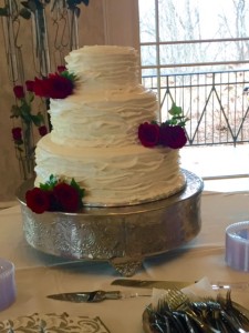 Elegant wedding cake adorned with fresh red roses.