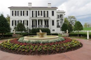 The side view of the mansion with a fountain and garden.