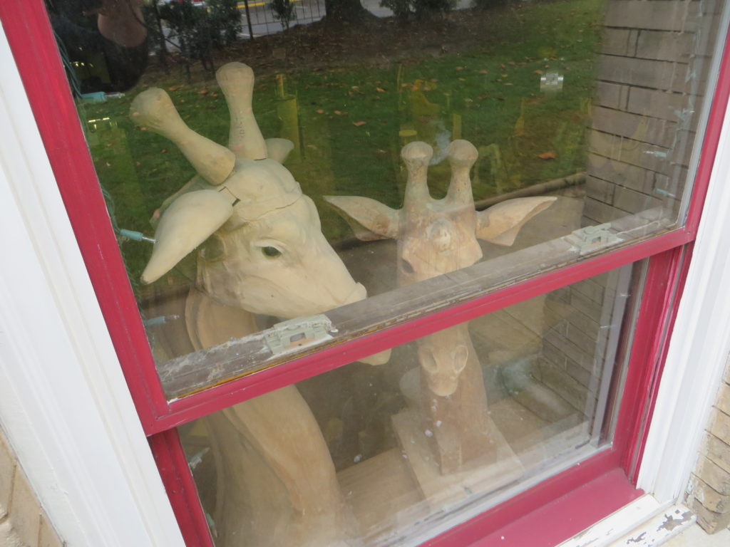 Unfinished giraffes sit in the window.