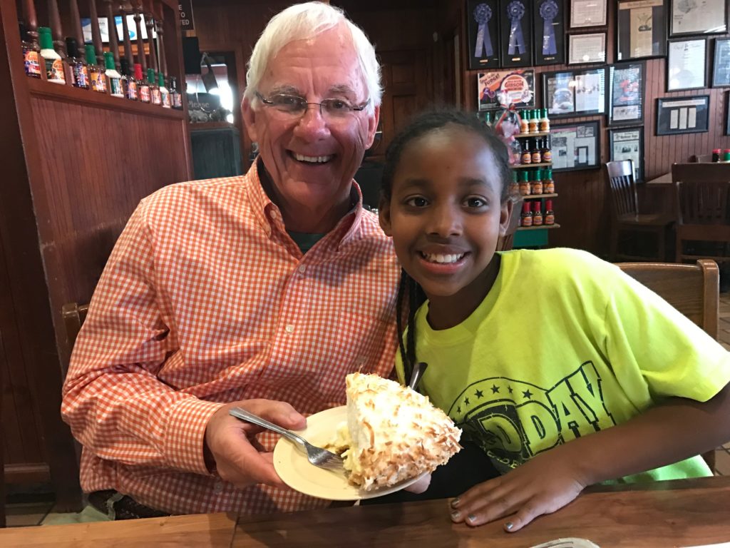 A granddaddy and granddaughter get ready to share a piece of pie. I wonder who ate the most? 