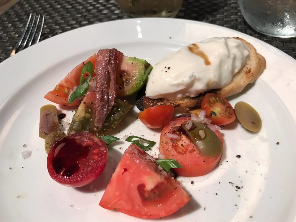 Cold plate with tomatoes, olives, an anchovy and Burrata cheese.
